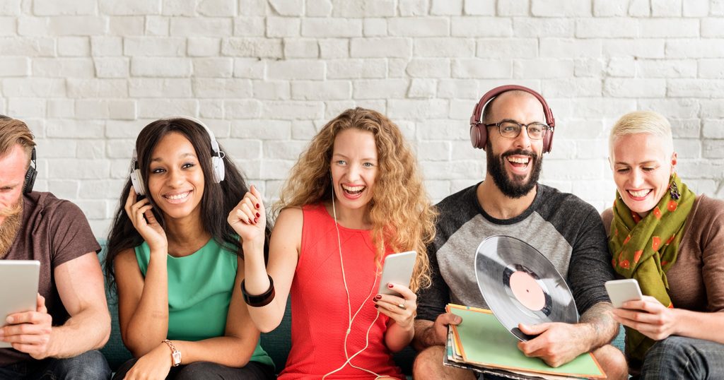 Group of young friends relaxing on a sofa, listening to music together